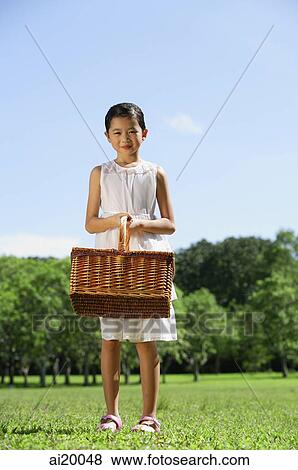 Stock Photo - Girl in white dress, holding picnic basket. Fotosearch