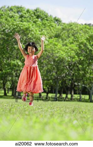 Stock Image - Girl running towards camera, arms outstretched, smiling. Fotosearch