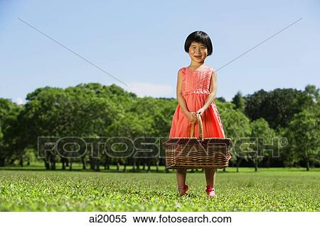 Stock Photography - Girl standing in park, holding picnic basket. Fotosearch