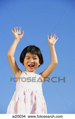 Girl with hands raised, smiling, looking at camera View Large Photo Image Picture - Girl with hands raised, smiling, looking at camera. Fotosearch