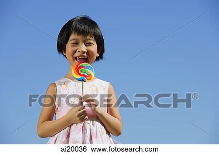 Stock Photograph - Girl with multi-coloured lollipop, portrait. Fotosearch