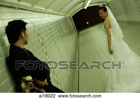 Groom leaning on tunnel wall, bride turning to look at groom View Large Photo Image Stock Image - Groom leaning on tunnel wall, bride turning to look at groom. Fotosearch