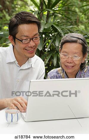 Picture - Grown son with mother, using laptop. Fotosearch