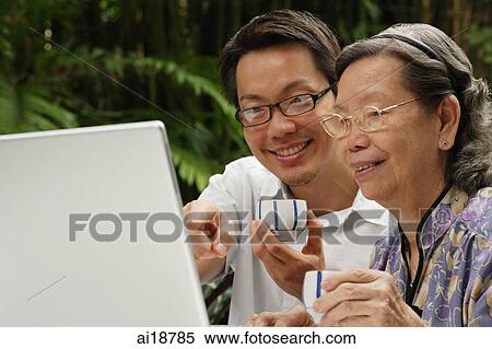 Grown son with mother, using laptop, both holding teacups View Large Photo Image Stock Photography - Grown son with mother, using laptop, both holding teacups. Fotosearch