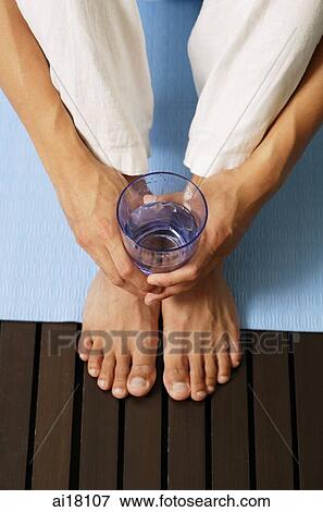 Stock Photo - High angle view, man holding glass of water, cropped image. Fotosearch
