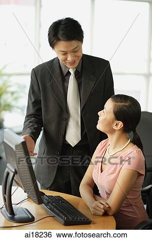 Male executive talking to seated female executive View Large Photo Image Stock Photograph - Male executive talking to seated female executive. Fotosearch