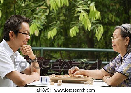 Man and senior woman sitting opposite each other playing a game of chess View Large Photo Image Stock Image - Man and senior woman sitting opposite each other playing a game of chess. Fotosearch