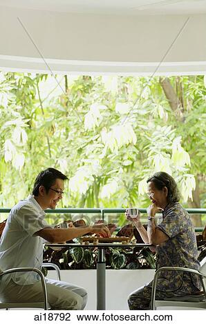 Stock Image - Man and senior woman sitting opposite each other in balcony playing a game of chess. Fotosearch