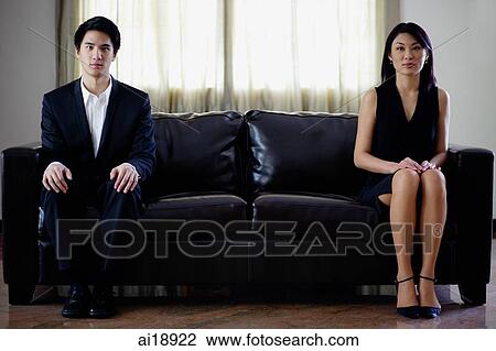 Stock Image - Man and woman sitting apart on sofa. Fotosearch