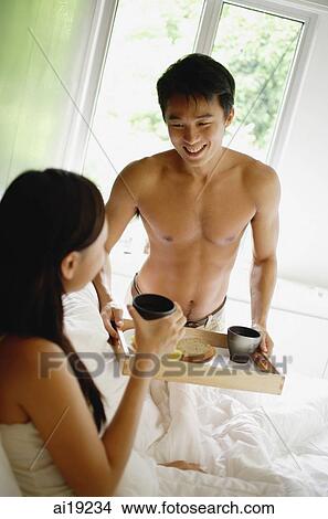 Picture - Man bringing woman breakfast in bed. Fotosearch
