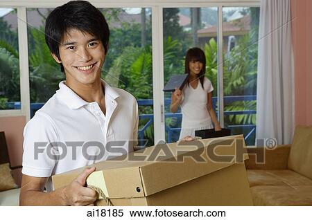 Man carrying a box, smiling at camera, woman in the background View Large Photo Image Stock Photography - Man carrying a box, smiling at camera, woman in the background. Fotosearch