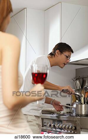 Man cooking in kitchen, woman in standing in foreground, holding wine glass View Large Photo Image Stock Image - Man cooking in kitchen, woman in standing in foreground, holding wine glass. Fotosearch