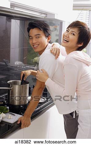 Man cooking on stove, woman embracing him from behind, both looking at camera View Large Photo Image Stock Image - Man cooking on stove, woman embracing him from behind, both looking at camera. Fotosearch