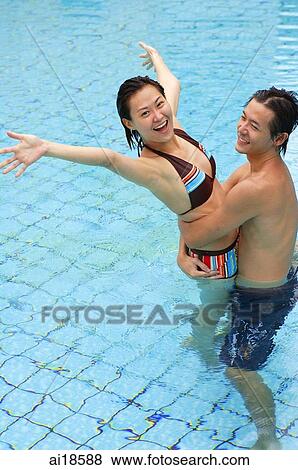 Man embracing woman in swimming pool, woman with arms outstretched View Large Photo Image Stock Photo - Man embracing woman in swimming pool, woman with arms outstretched. Fotosearch