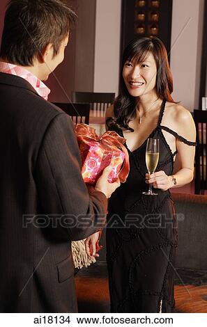 Man giving gift to woman in front of him View Large Photo Image Picture - Man giving gift to woman in front of him. Fotosearch