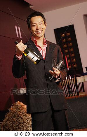 Man holding bottle of wine and two glasses, smiling at camera View Large Photo Image Stock Photo - Man holding bottle of wine and two glasses, smiling at camera. Fotosearch