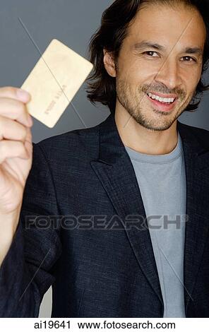 Stock Image - Man holding credit card, smiling. Fotosearch