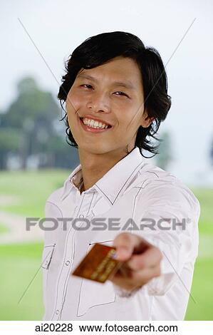 Man holding credit card, towards camera, smiling View Large Photo Image Stock Photo - Man holding credit card, towards camera, smiling. Fotosearch