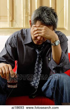 Man holding drink, looking down, hand on head View Large Photo Image Stock Image - Man holding drink, looking down, hand on head. Fotosearch