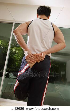 Man holding foot behind his back, stretching View Large Photo Image Stock Photograph - Man holding foot behind his back, stretching. Fotosearch