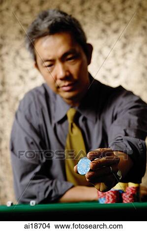 Picture - Man holding gambling chip. Fotosearch