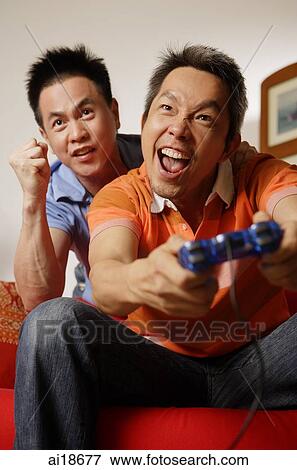 Man holding game controller, mouth open, man behind him making a fist View Large Photo Image Stock Photo - Man holding game controller, mouth open, man behind him making a fist. Fotosearch