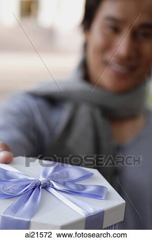 Stock Image - Man holding gift box, selective focus. Fotosearch
