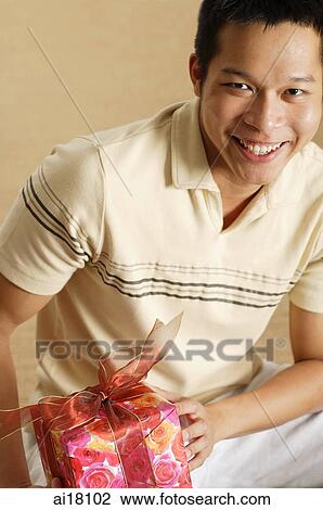 Man holding gift, smiling at camera View Large Photo Image Stock Image - Man holding gift, smiling at camera. Fotosearch