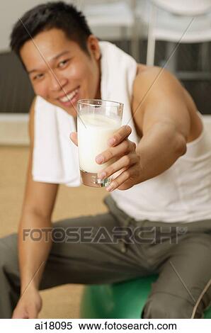 Man holding glass of milk towards camera View Large Photo Image Stock Photography - Man holding glass of milk towards camera. Fotosearch