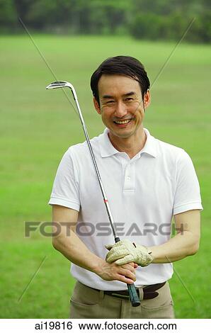 Stock Photograph - Man holding golf club, looking at camera. Fotosearch