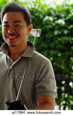 Man holding golf club, smiling at camera View Large Photo Image Picture - Man holding golf club, smiling at camera. Fotosearch