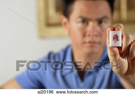 Stock Photograph - Man holding mahjong dice towards camera. Fotosearch