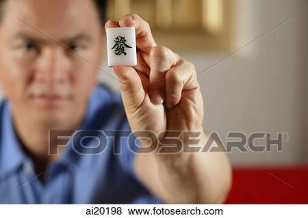 Stock Photo - Man holding mahjong dice with the word Luck. Fotosearch