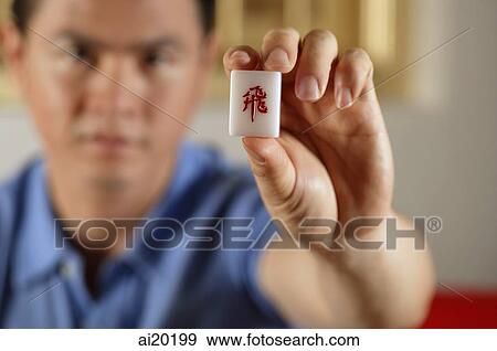 Stock Photo - Man holding mahjong tile. Fotosearch