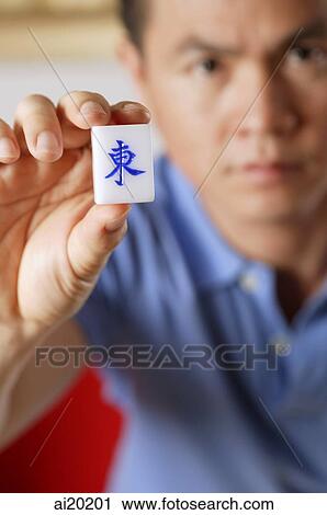 Man holding mahjong tile with Chinese script meaning East View Large Photo Image Stock Image - Man holding mahjong tile with Chinese script meaning East. Fotosearch