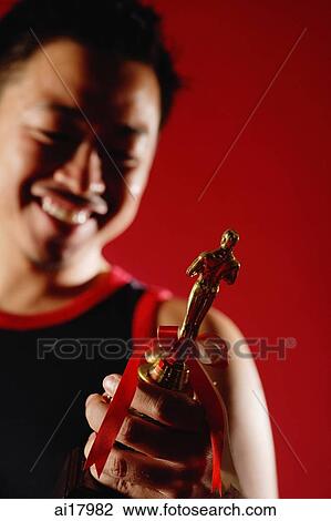 Stock Image - Man holding trophy. Fotosearch