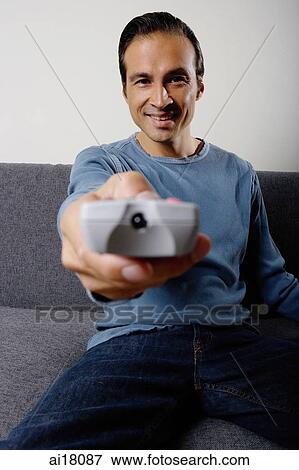 Man holding TV remote control, pointing towards camera View Large Photo Image Stock Photo - Man holding TV remote control, pointing towards camera. Fotosearch