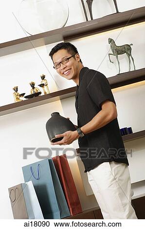 Man holding vase in shop, smiling at camera View Large Photo Image Stock Image - Man holding vase in shop, smiling at camera. Fotosearch