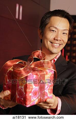 Man holding wrapped gift, smiling View Large Photo Image Stock Image - Man holding wrapped gift, smiling. Fotosearch