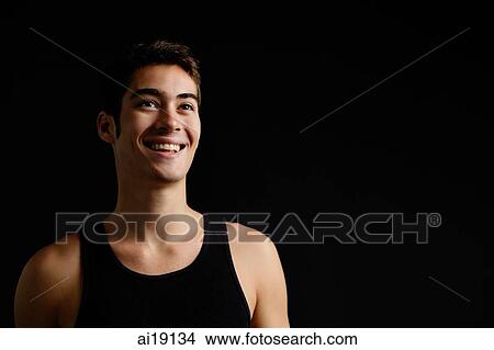 Man in black sleeveless top, standing against black background, looking away, smiling View Large Photo Image Picture - Man in black sleeveless top, standing against black background, looking away, smiling. Fotosearch