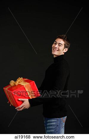 Man in black turtleneck carrying big red box with gold ribbon View Large Photo Image Stock Photo - Man in black turtleneck carrying big red box with gold ribbon. Fotosearch