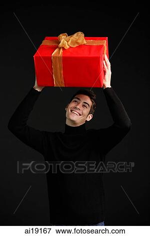 Man in black turtleneck, holding wrapped present over his head View Large Photo Image Stock Photo - Man in black turtleneck, holding wrapped present over his head. Fotosearch