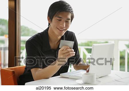 Man in cafe using laptop and holding credit card View Large Photo Image Stock Photography - Man in cafe using laptop and holding credit card. Fotosearch