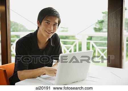 Man in cafe using laptop, smiling at camera View Large Photo Image Stock Image - Man in cafe using laptop, smiling at camera. Fotosearch