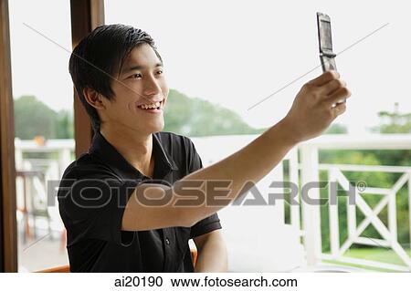Man in cafe using mobile phone to take a picture of himself View Large Photo Image Stock Image - Man in cafe using mobile phone to take a picture of himself. Fotosearch
