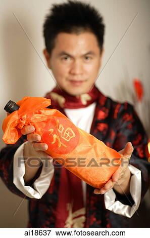 Man in Chinese costume, holding wine bottle towards camera View Large Photo Image Stock Photo - Man in Chinese costume, holding wine bottle towards camera. Fotosearch