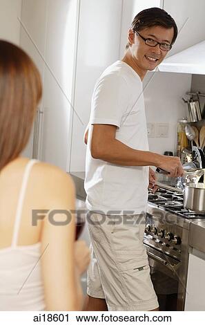Man in kitchen, standing by stove, turning to smile at woman View Large Photo Image Stock Image - Man in kitchen, standing by stove, turning to smile at woman. Fotosearch