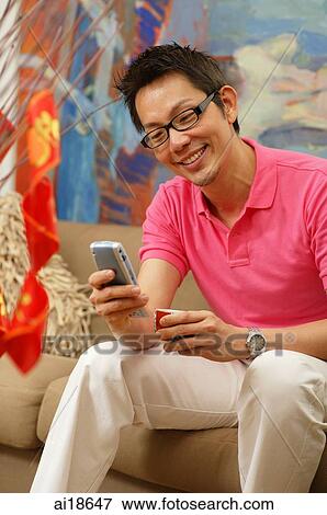 Man in pink polo shirt holding mobile phone View Large Photo Image Stock Photo - Man in pink polo shirt holding mobile phone. Fotosearch