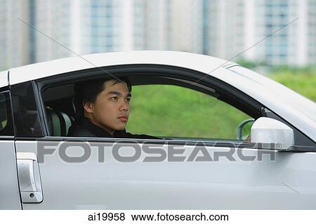 Stock Photo - Man in silver car, looking away. Fotosearch