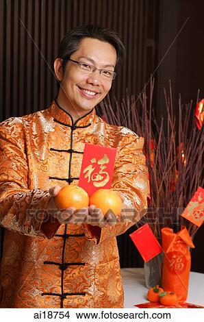 Man in traditional Chinese clothing holding oranges and red packet View Large Photo Image Picture - Man in traditional Chinese clothing holding oranges and red packet. Fotosearch
